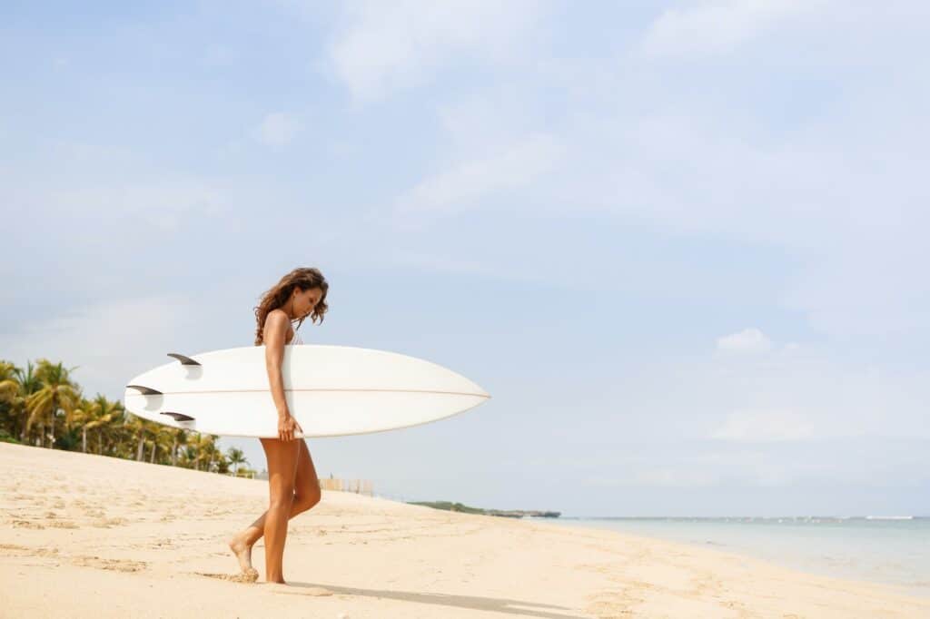 Beautiful sporty surfer girl at the beach.