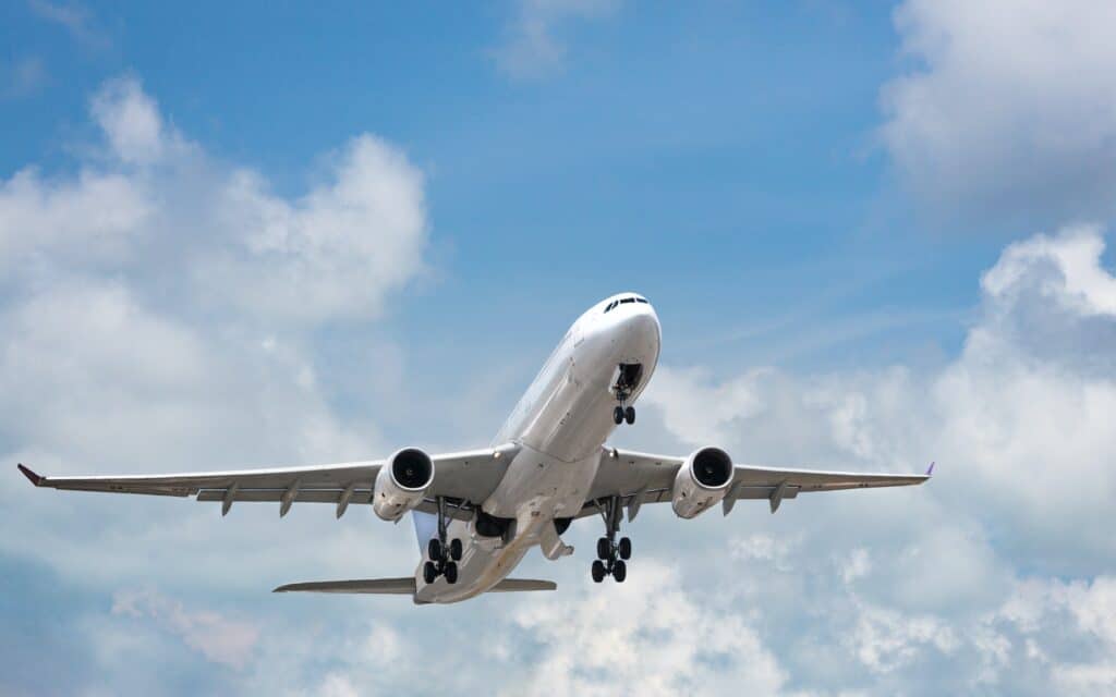 Passenger airplane taking off in bright cloudy sky. Wide-body commercial airliner over blue sky