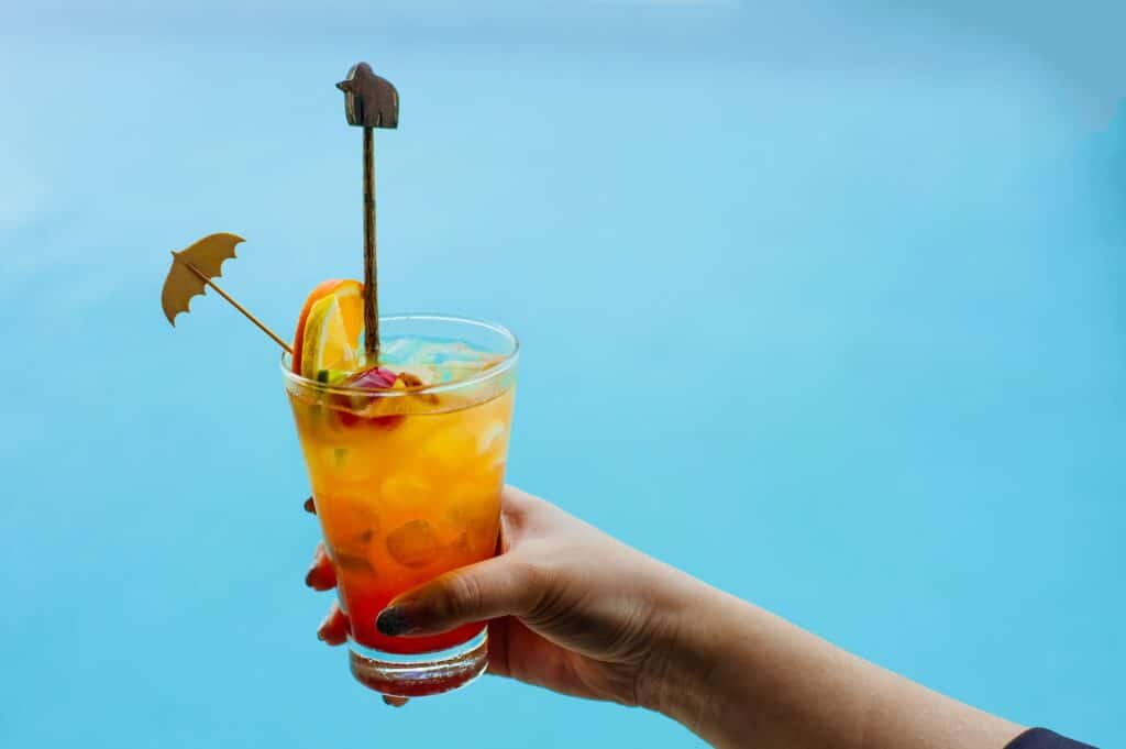 Woman holds a cocktail on swimming pool background.fresh tropical juice cocktail served pool.