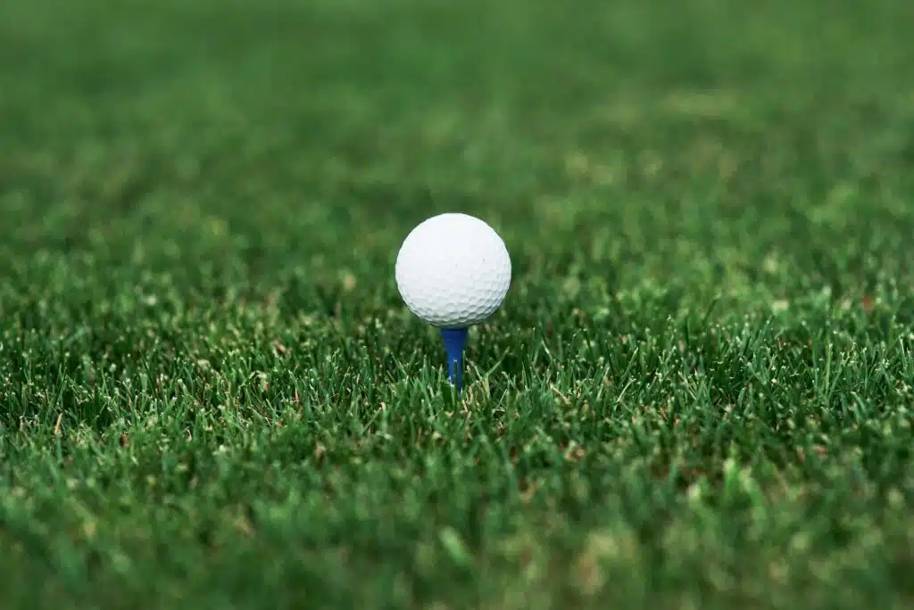 Close up photo of golf ball standing on the pin in the green lawn