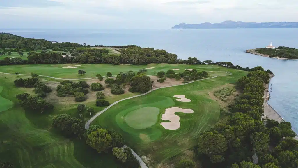 Grüner Golfplatz auf einem Hügel nahe dem Meer an einem bewölkten Tag auf Mallorca, Spanien