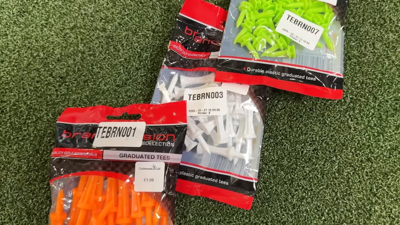 Verschiedene bunte Golf‑Tees in Verpackungen auf Kunstrasen